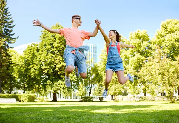 Glad tonåring par hoppar på sommaren park — Stockfoto