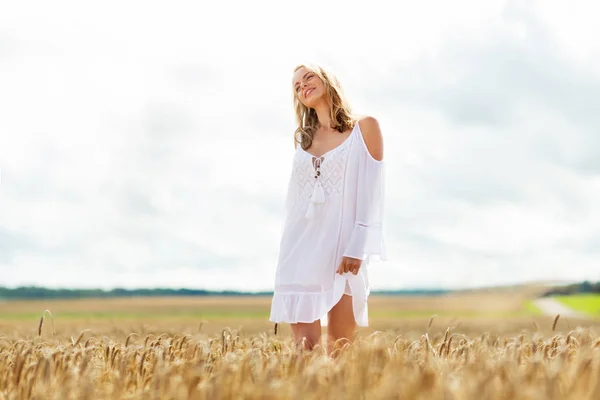 Usmívající se mladá žena v bílých šatech na obilném poli — Stock fotografie