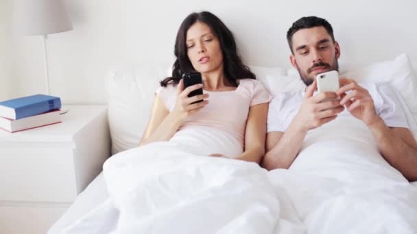 Casal feliz com smartphones na cama — Vídeo de Stock