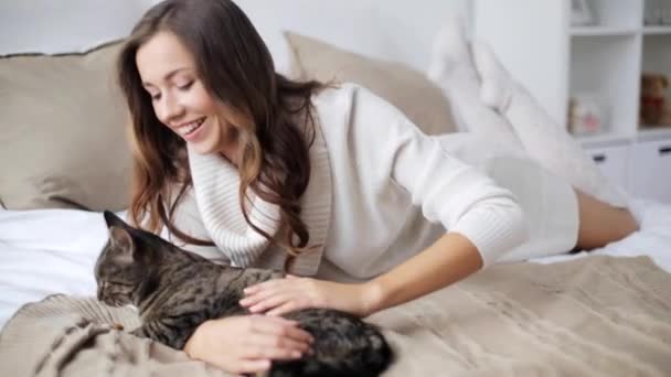 Feliz joven con gato comiendo en la cama en casa — Vídeo de stock