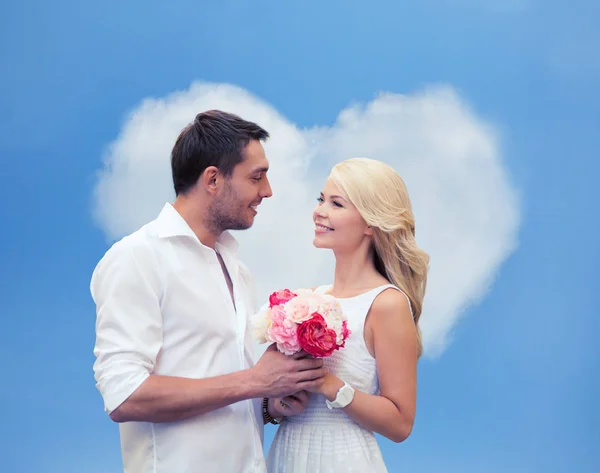 Happy couple with flowers over heart shaped cloud — Stock Photo, Image