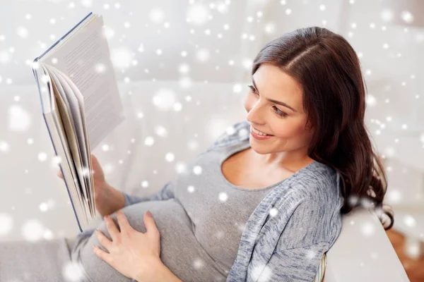 Счастливая беременная женщина читает книгу дома — стоковое фото