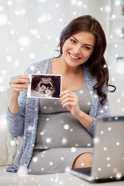 Счастливая беременная женщина с ультразвуком изображения дома — стоковое фото