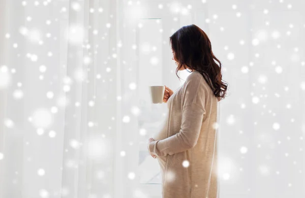 Primer plano de la mujer embarazada con taza de té en la ventana — Foto de Stock