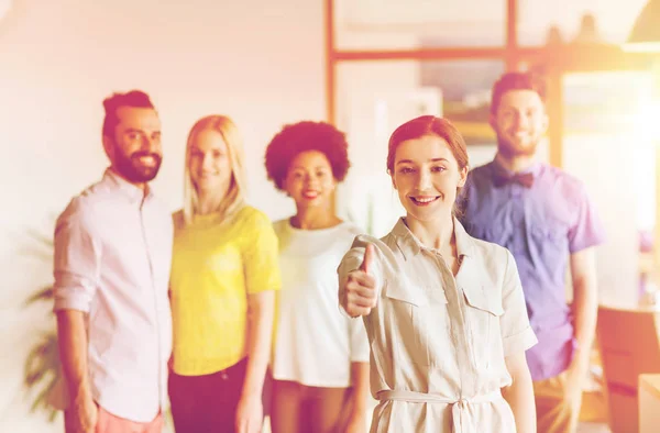 Mujer mostrando pulgares hacia arriba sobre el equipo de oficina creativa — Foto de Stock