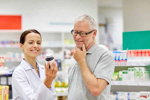 Pharmacist showing drug to senior man at pharmacy — Stock Photo, Image
