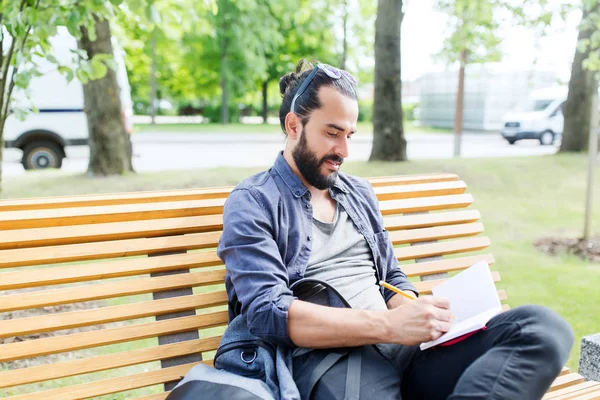 Hombre escribiendo a cuaderno o diario en la calle de la ciudad — Foto de Stock