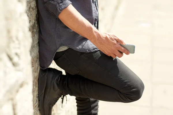 Закрыть человека со смартфоном у каменной стены — стоковое фото