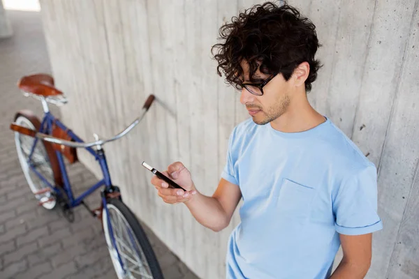 Hombre con teléfono inteligente y bicicleta de engranaje fijo en la calle —  Fotos de Stock