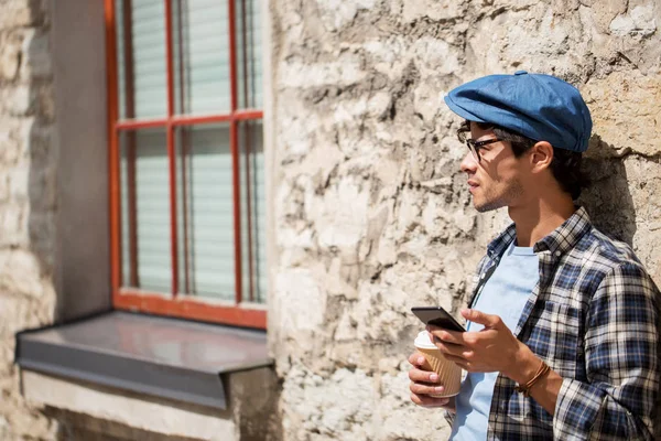 Man with smartphone drinking coffee on city street — Stock Photo, Image