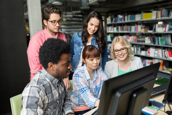 Studenti internazionali con computer in biblioteca — Foto Stock
