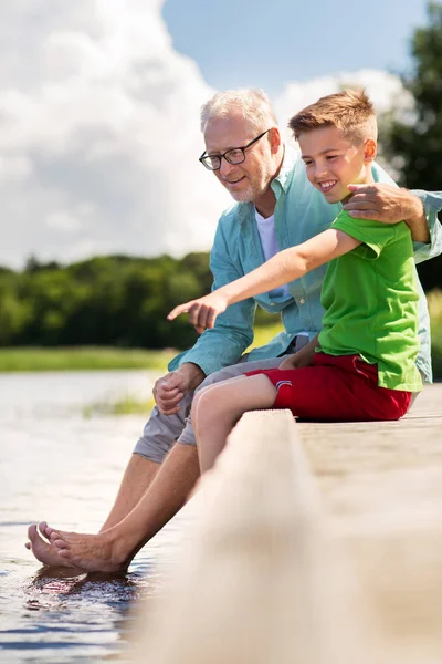 Nagyapa és unokája ül a folyó kikötőjében — Stock Fotó