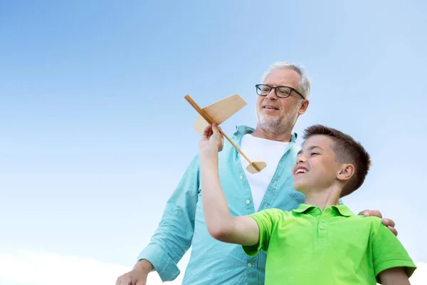 Senior man and boy with toy airplane over sky — Stock Photo, Image