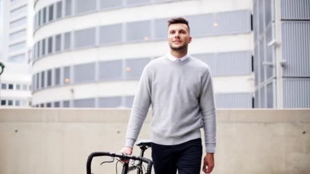 Jovem caminhando ao longo da rua da cidade com bicicleta — Vídeo de Stock