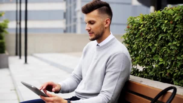 Man with tablet pc sitting on city street bench — Stock Video