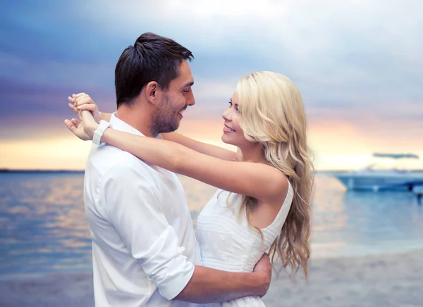 Feliz pareja abrazándose sobre el fondo de la playa puesta del sol — Foto de Stock