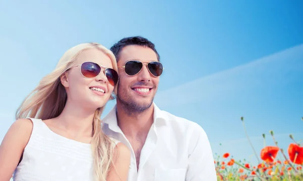 Happy couple in shades over poppy field background — Stock Photo, Image