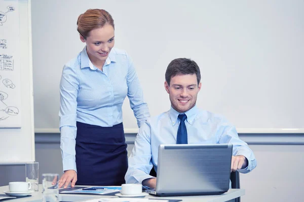 Empresarios sonrientes con portátil en la oficina —  Fotos de Stock