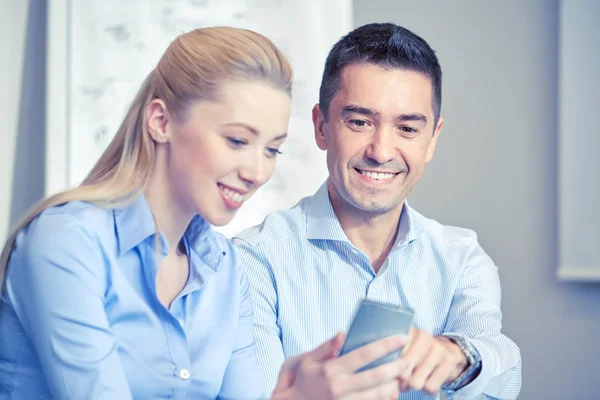 Empresarios sonrientes con smartphones en la oficina —  Fotos de Stock