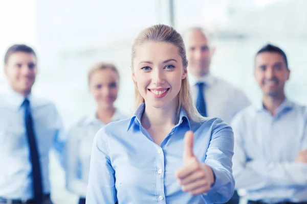 Smiling businesswoman showing thumbs up in office — Stock Photo, Image