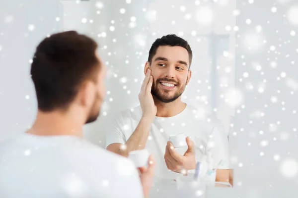 Felice giovane uomo che applica la crema al viso in bagno — Foto Stock