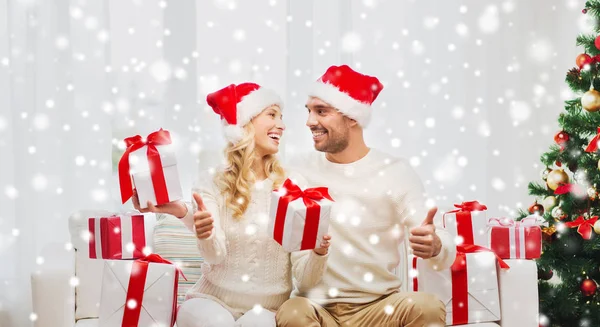 Feliz pareja con regalos de Navidad y pulgares hacia arriba — Foto de Stock