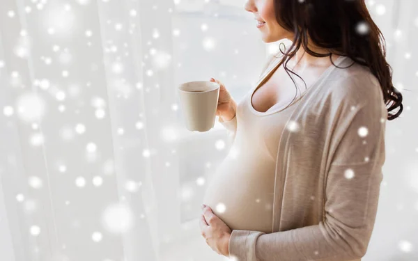 Close up of pregnant woman with tea cup at window — Stock Photo, Image