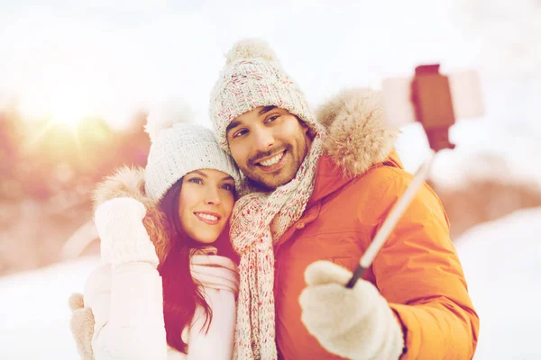 Feliz pareja tomando selfie por teléfono inteligente en invierno — Foto de Stock