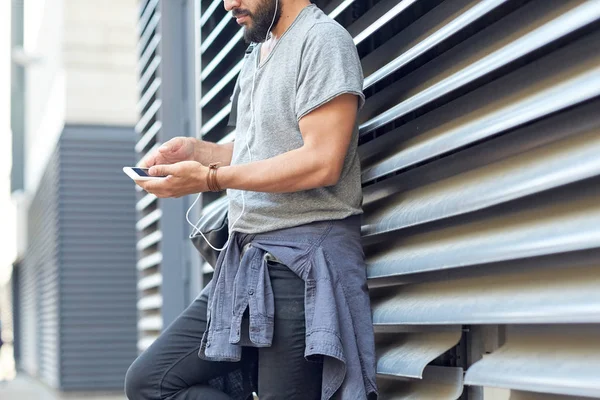 Uomo con auricolari, smartphone e borsa in strada — Foto Stock