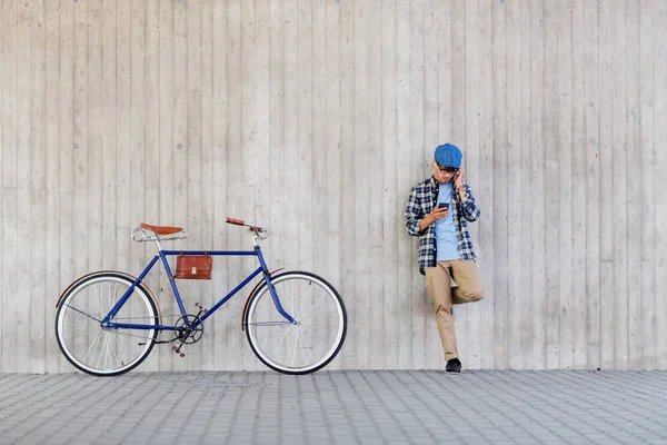 Hipster hombre en auriculares con smartphone y bicicleta —  Fotos de Stock