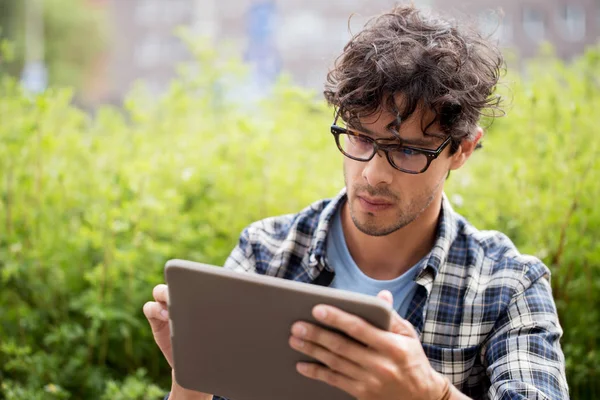 Man in glasses with tablet pc computer outdoors — Stock Photo, Image