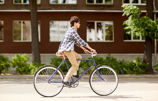 Çantalı genç hippi sabit vitesli bisiklet sürüyor. — Stok fotoğraf