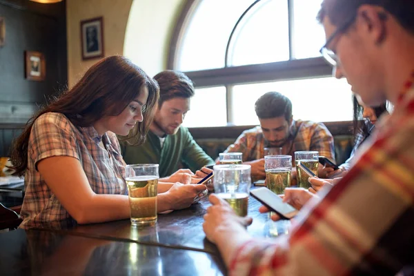 Vrienden met smartphones en bier bij bar of pub — Stockfoto