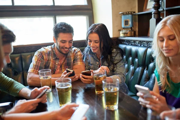 Friends with smartphones and beer at bar or pub — Stock Photo, Image