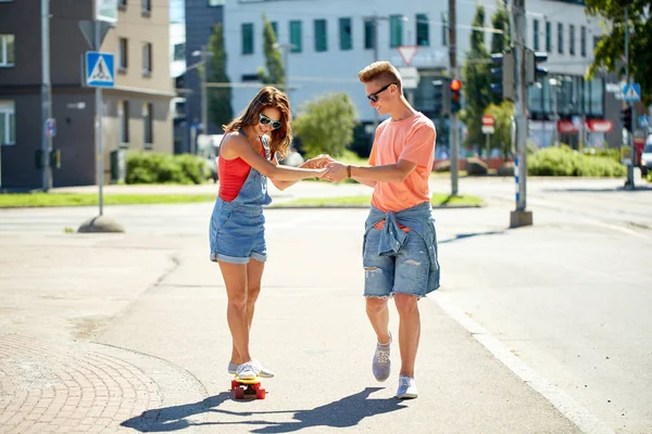 Pareja adolescente montando monopatines en la calle de la ciudad — Foto de Stock