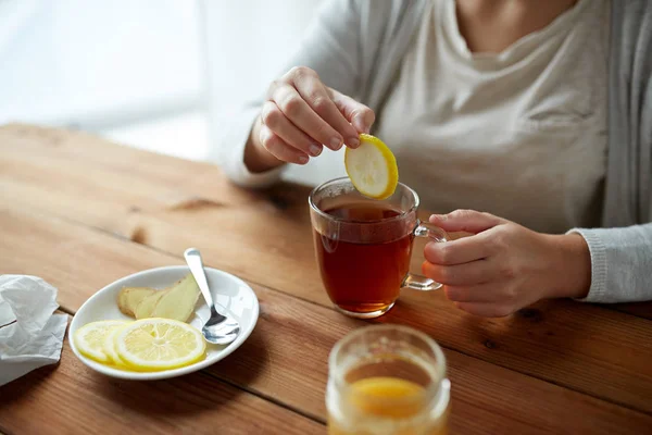 Close up of woman adding lemon to tea cup — Stock Photo, Image