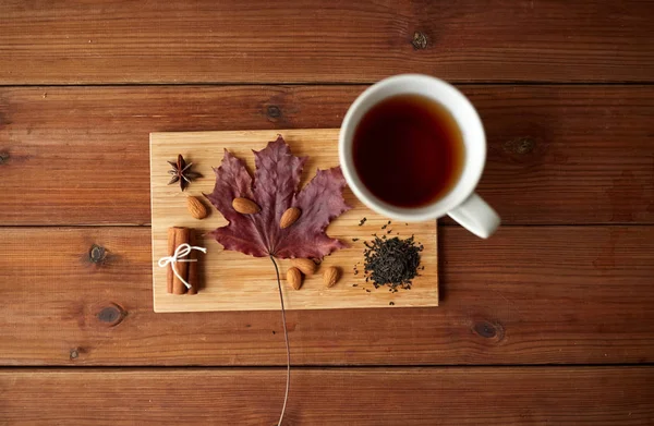 Herbatę, liść klonu i migdałów na desce — Zdjęcie stockowe