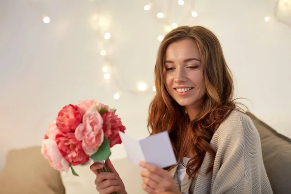 Donna felice con fiori e biglietto di auguri a casa — Foto Stock
