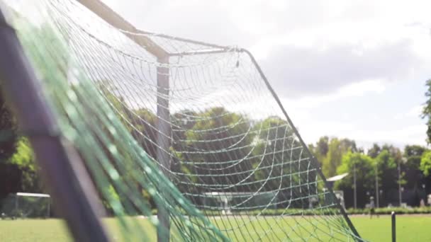 Мяч летит в футбольную сетку ворот на поле — стоковое видео