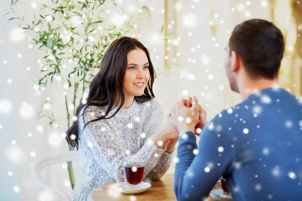 Happy couple with tea holding hands at restaurant — Stock Photo, Image