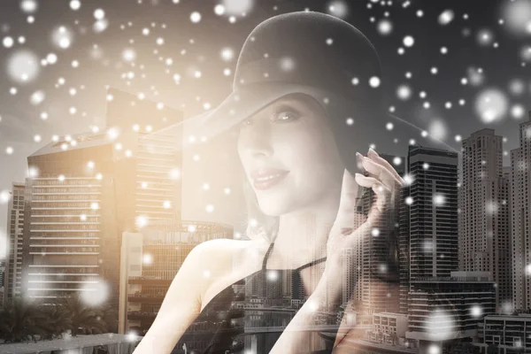 Mujer en sombrero negro sobre fondo de ciudad y nieve —  Fotos de Stock