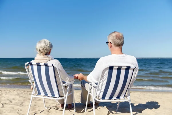 Seniorenpaar sitzt auf Stühlen am Sommerstrand — Stockfoto