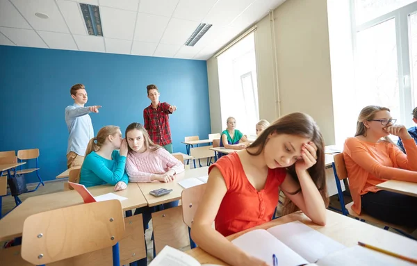 Estudiantes chismorreando detrás de su compañero de clase en la escuela —  Fotos de Stock