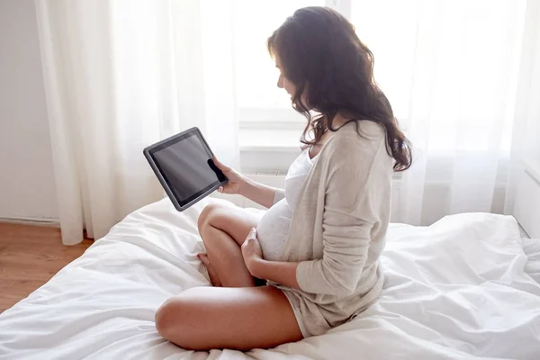 Zamknij się kobieta w ciąży z komputera typu tablet w domu — Zdjęcie stockowe