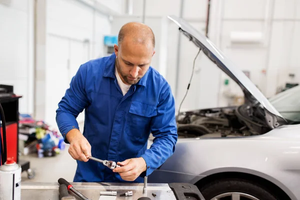 Monteur met moersleutel reparatie auto op de werkplaats — Stockfoto
