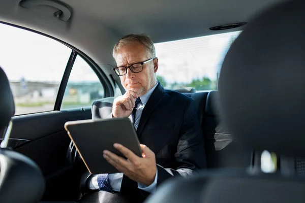 Empresário sênior com tablet pc dirigindo no carro — Fotografia de Stock