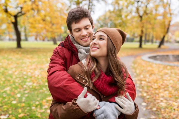 Счастливая молодая пара обнимается в осеннем парке — стоковое фото