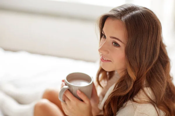Mujer feliz con taza de cacao en la cama en casa — Foto de Stock
