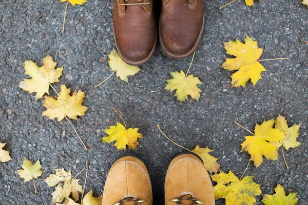 Paio di piedi in stivali e foglie di autunno — Foto Stock