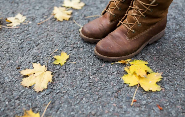 Piedi femminili in stivali e foglie autunnali — Foto Stock